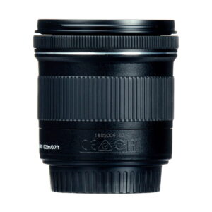Lähikuva Canon EF-S 10-18mm f/4.5-5.6 IS STM -objektiivista näyttää sen mustat, kuvioidut tarkennusrenkaat ja zoomausrenkaat, joissa on valkoisia merkintöjä ja symboleja lähellä pohjaa, kaikki valkoista taustaa vasten.