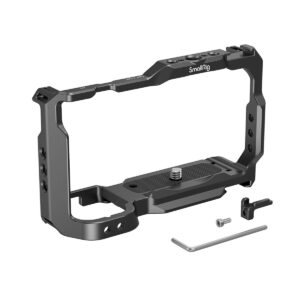 Kuvassa näkyy mustaa metallia oleva SmallRig Cage for Sony ZV-E10 3531, joka on suunniteltu pitämään kamera tukevasti paikallaan. Kuvassa on myös kiinnitysruuvi, pieni kiinnike, kuusiokoloavain ja pieni ruuvi valkoisella pohjalla.