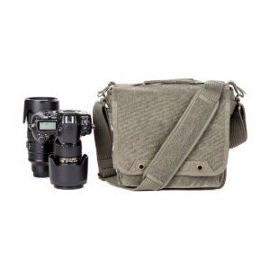 Think Tank Retrospective 10 V2.0 - Pinestone, vihreä kangasolkalaukku, on sijoitettu DSLR-kameran ja kahden objektiivin viereen valkoiselle taustalle.