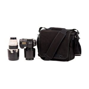 The Think Tank Retrospective 20 V2.0 - Black sits next to a DSLR camera with attached lens and a separate telephoto lens, both with lens covers, all set against a white background.