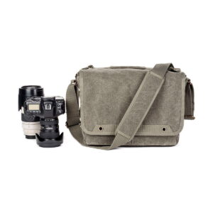 Think Tank Retrospective 30 V2.0 - Pinestone -kameralaukku istuu mustan DSLR-kameran rungon ja kahden vaihdettavan objektiivin vieressä valkoisella taustalla.