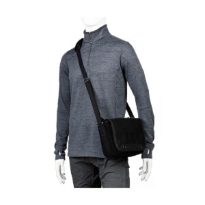 Harmaaseen pitkähihaiseen quarter-zip-paitaan ja tummanharmaisiin housuihin pukeutunut mallinukke kantaa Think Tank Retrospective 4 V2.0 - Musta crossbody messenger -laukkua olkapäällä.