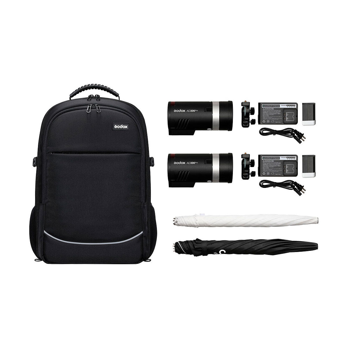 Godox AD300 Pro Outdoor 2-Flash Kit sisältää mustan repun, kaksi AD300 Pro -salamalaitetta, laturit akkuineen ja virtajohtoineen sekä yhden valkoisen ja yhden mustan taitetun sateenvarjon valkoisella pohjalla.