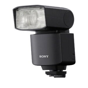 Musta Sony HVL-F46RM -kameran ulkoinen salama, jossa on suorakulmainen, hieman ylöspäin kallistettu pää, on asennettu kuuman kengän jalustalle valkoista taustaa vasten.