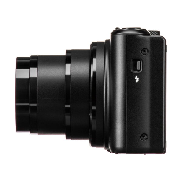The black Canon PowerShot SX740 HS compact camera, with the lens extended, is shown sideways against a white background. A flash symbol appears on the body above a small button.