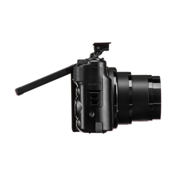 The Canon PowerShot SX740 HS compact camera is shown from the side, with its LCD screen turned out and at an angle, pop-up flash raised and lens fully extended.