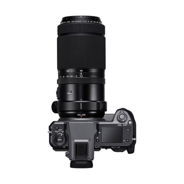 Fujifilm GFX 100 -digitaalikamera, jossa on suuri teleobjektiivi, ylhäältä kuvattuna valkoista taustaa vasten. Kameran rungossa on näyttö, painikkeet ja etsin.