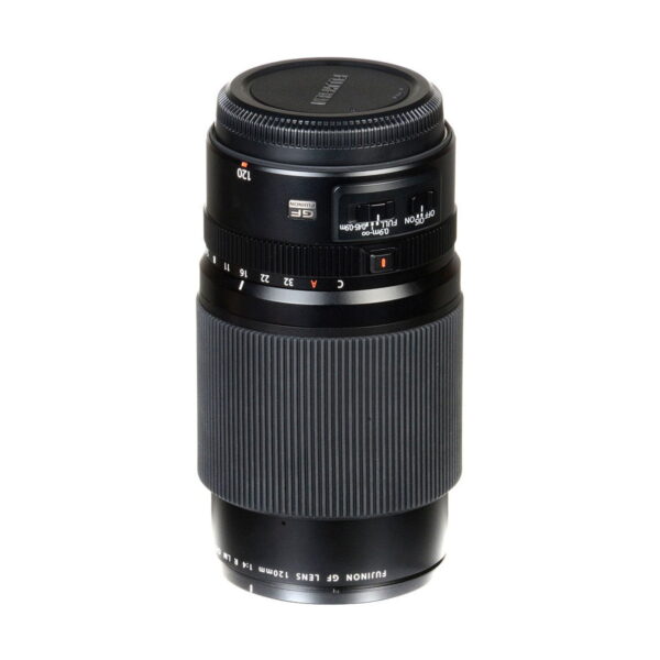 Fujinon_120mm_f_4_Macro_R_LM_OIS_WR_003 Fujifilm Fujinon GF 120mm f/4 Macro R LM OIS WR -objektiivi mustana, jossa on kuvioitu tarkennusrengas, aukon merkinnät ja objektiivin suojus, seisoo pystyssä valkoisella taustalla.