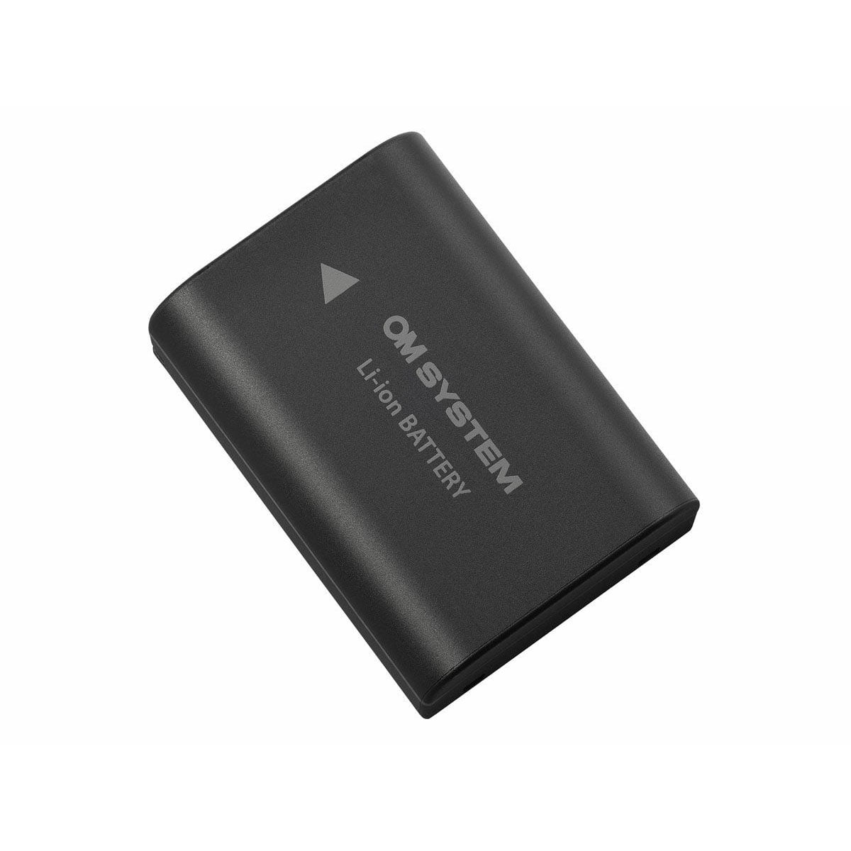 Musta OM SYSTEM BLX-1 akku litiumioniakku, jonka pinnalla on valkoinen nuoli ja teksti "Li-ion BATTERY", valkoista taustaa vasten.