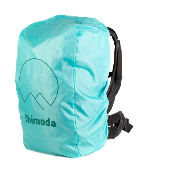 Mustan Shimoda Designs Explore v2 25 Starter Kit -kamerarepun, jossa on pehmustetut olkahihnat ja vyötäröhihna, päälle on asennettu turkoosi sadesuoja, jossa on "Shimoda" ja vuoristologo.
