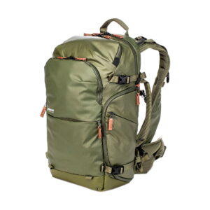 The Shimoda Designs Explore v2 25 Starter Kit Camera Backpack in green features multiple zippered compartments, adjustable padded straps, side compression straps, tan zipper pulls, a sturdy rectangular shape and a waist belt for extra support.