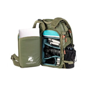 Shimoda Designs Explore v2 25 Starter Kit Camera Backpack, green, includes a side compartment that opens to hold camera gear, lenses, a blue hard case and a silver laptop on a padded sleeve. A black mesh water bottle holder is attached to the side.