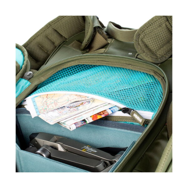 Close-up of the Shimoda Designs Explore v2 25 Starter Kit camera backpack, green, opened to reveal a blue mesh pocket with folded maps and a lower compartment to hold a folded black drone.