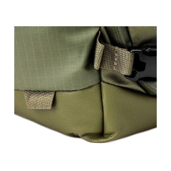 Close up of the Shimoda Designs Explore v2 25 Starter Kit camera backpack, green with visible green and olive green fabric, visible stitching, strap ties, plastic buckle and detailed material construction.