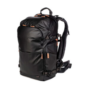 The Shimoda Designs Explore v2 30 Camera Backpack, Black is a black, weatherproof camera backpack with multiple compartments and padded shoulder straps. It has orange zipper pulls and is photographed vertically on a white background.