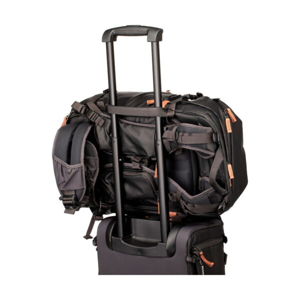 The Shimoda Designs Explore v2 30 camera backpack, black, is attached to a rolling suitcase with extended handles and organized storage pockets.