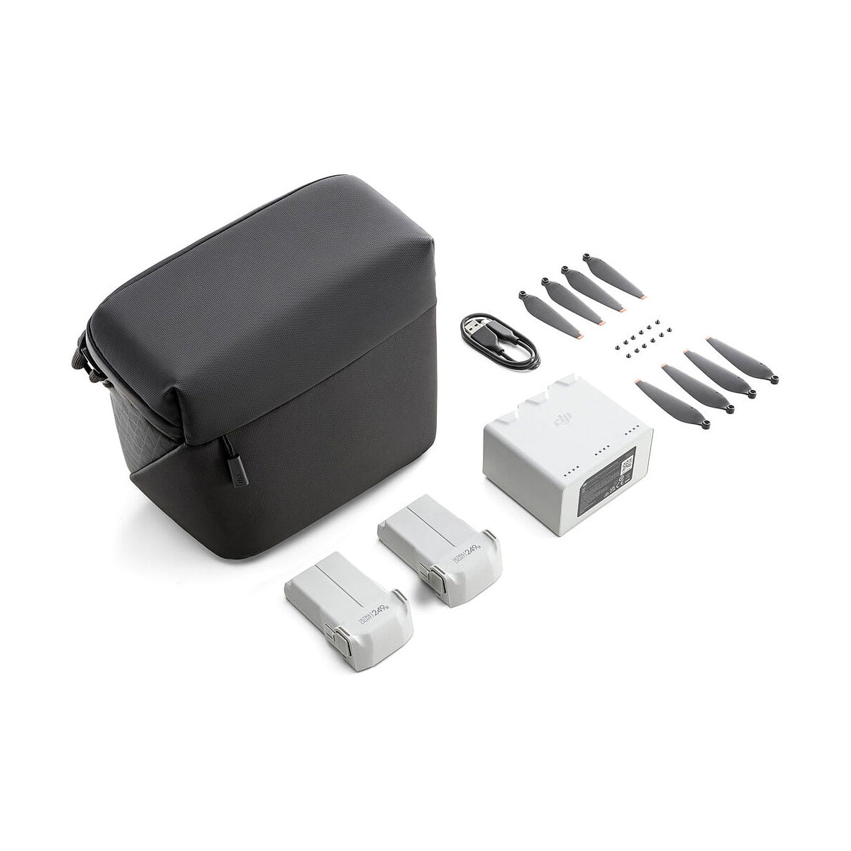 DJI Mini 3 Pro Fly More Kit sisältää mustan kantolaukun, kaksi harmaata akkua, latauskeskittimen, USB-kaapelin, kuusi potkuria ja pieniä ruuveja - kaikki valkoisella pohjalla.