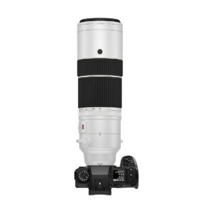 Digitaalikamera, jossa on Fujifilm Fujinon XF 150-600mm f/5.6-8 R LM OIS WR -objektiivi, näkyy ylhäältä päin valkoista taustaa vasten, jolloin kameran yläosan säätimet ja nestekidenäyttö korostuvat. Nyt 400€ alennuksella.