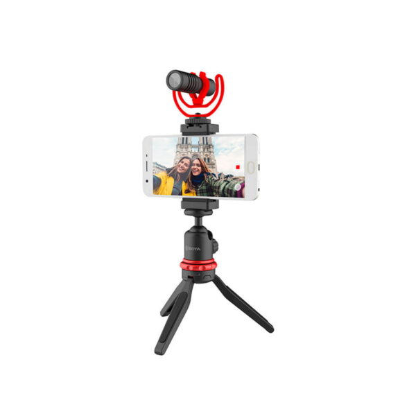 Älypuhelin on kiinnitetty Boya BY-VG330 Video-Kit -malliin, joka on kompakti musta-punainen jalusta, jossa on ulkoinen mikrofoni, ja näyttää selfien kahdesta ihmisestä maamerkin luona.