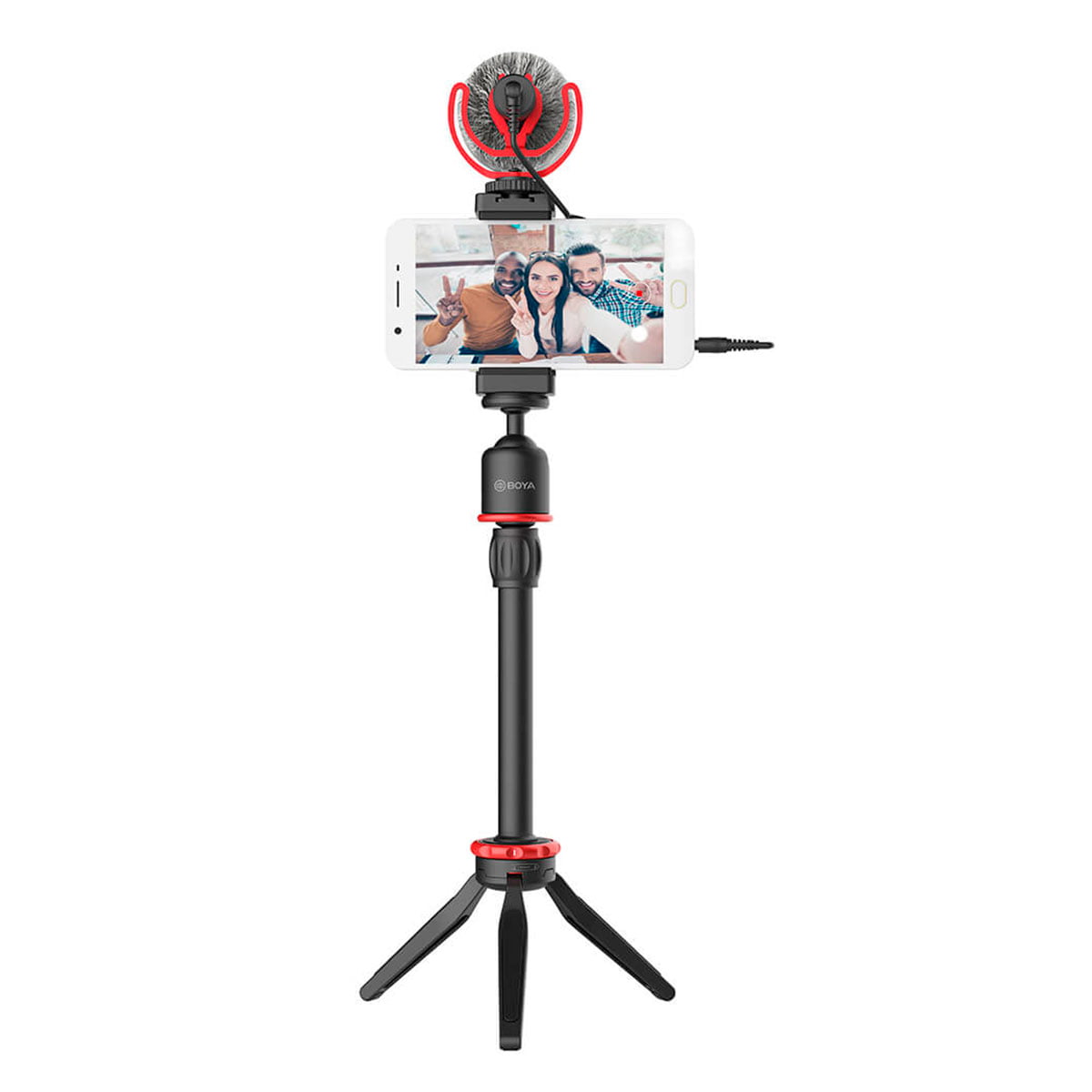 Boya BY-VG330 Video-Kit pitää älypuhelinta, joka on kiinnitetty mustaan jalustaan, jossa on punaiset korostukset, ja sen päälle on kiinnitetty pieni ulkoinen mikrofoni. Puhelimen näytöllä näkyy kaksi ihmistä ottamassa selfietä.