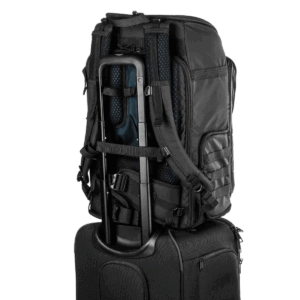 Tenba Axis V2 32L Backpack -kamerareppu mustana, jossa on pehmustetut hihnat ja useita lokeroita, on kiinnitetty matkalaukkukahvaan, joka esittelee sen tyylikästä, matkaystävällistä muotoilua.