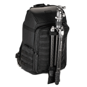 Tenba Axis V2 32L Backpack -kamerareppu on musta kamerareppu, jossa on useita lokeroita ja vetoketjuja ja jossa on hiilikuituinen kolmijalka, joka on kiinnitetty turvallisesti eteen.
