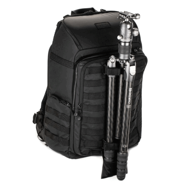 Tenba Axis V2 32L Backpack -kamerareppu on musta kamerareppu, jossa on useita lokeroita ja vetoketjuja ja jossa on hiilikuituinen kolmijalka, joka on kiinnitetty turvallisesti eteen.