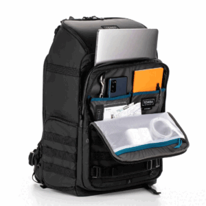 Tenba Axis V2 32L Backpack -kamerareppu on kuvassa mustana, etulokero auki, ja siihen mahtuu useisiin taskuihin siististi kannettava tietokone, tabletti, älypuhelin, oranssi muistikirja, kyniä, papereita, latausjohto ja tarvikkeet.