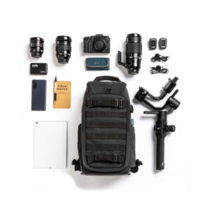 Tasokuva valokuvauskalustosta, johon kuuluu Tenba Axis V2 16L Backpack -kamerareppu, kolme kameran objektiivia, kamera, kaksi muistikorttia, kaapelit, älypuhelin, muistilappu, kynä, kovalevy, tabletti ja kameran gimbal.