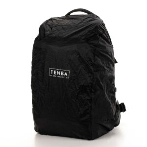 Tenba Axis V2 24L Backpack -kamerareppu on musta laukku, jossa on ryppyinen rakenne ja jonka etupuolella on valkoinen TENBA NEW YORK 1977 -logo. Se seisoo pystyssä tavallista valkoista taustaa vasten.