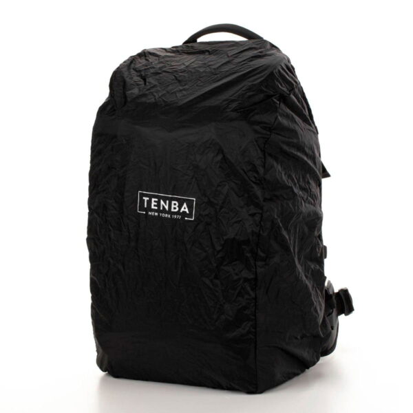 Tenba Axis V2 24L Backpack -kamerareppu on musta laukku, jossa on ryppyinen rakenne ja jonka etupuolella on valkoinen TENBA NEW YORK 1977 -logo. Se seisoo pystyssä tavallista valkoista taustaa vasten.