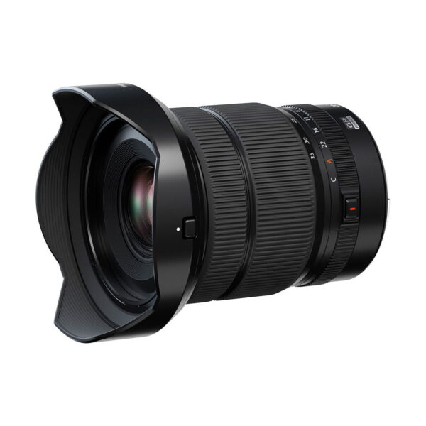 The Fujifilm Fujino GF 20-35mm f/4 R WR lens has a large front glass, textured zoom and focus rings, side control switches, petal-shaped hood, and is black, slightly askew in the photo.