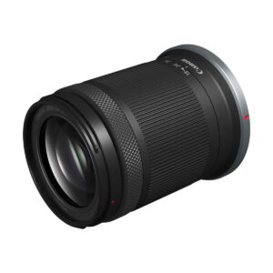 Canon RF-S 18-150mm f/3.5-6.3 IS STM -objektiivi, jossa on musta runko ja kuvioitu tarkennusrengas, on sijoitettu kulmassa valkoista taustaa vasten.