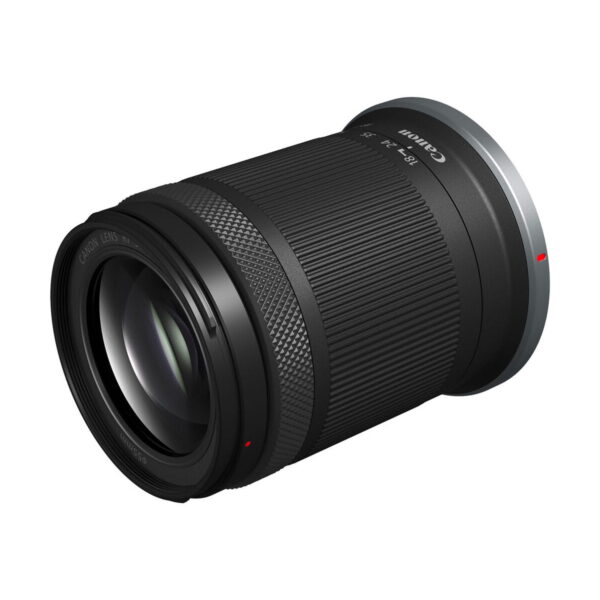 Canon RF-S 18-150mm f/3.5-6.3 IS STM -objektiivi, jossa on musta runko ja kuvioitu tarkennusrengas, on sijoitettu kulmassa valkoista taustaa vasten.