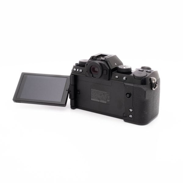Fujifilm X-S10 (SC 1189)- Käytetty digikamera on kuvattu takaa valkoisella taustalla, ja siinä on kuvioitu kahva ja sen LCD-näyttö on käännetty vasemmalle, jolloin näyttö on tyhjä ja tumma.