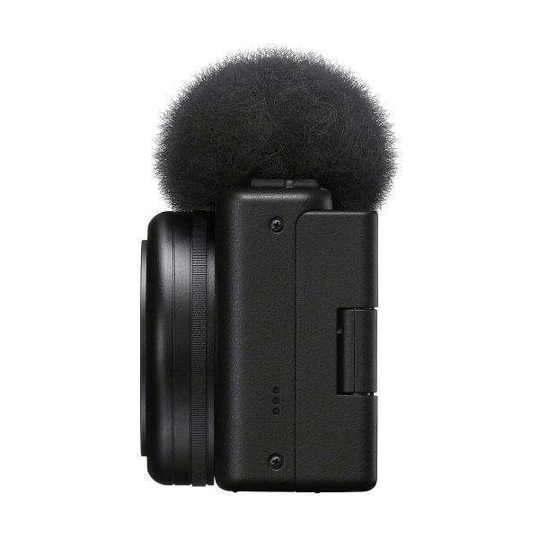 Sivukuva Sony ZV-1F -kompaktikamerasta, kompaktista mustasta digitaalikamerasta, jossa on objektiivi ja sumea tuulisuoja äänen kohinan vähentämiseksi, eristettynä valkoiselta taustalta.