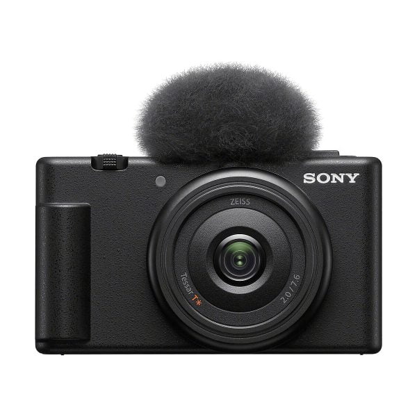 Etukuva mustasta Sony ZV-1F -kompaktikamerasta, jossa on suuri pyöreä linssi ja siihen kiinnitetty sumea tuulilasi, joka on suunniteltu vähentämään melua äänitallennuksen aikana.