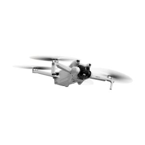 The DJI Mini 3 + Smart Controller drone, with its sleek white design, four extended arms and rotating propellers, flies against a white background. The front camera adds to its compact and modern look.