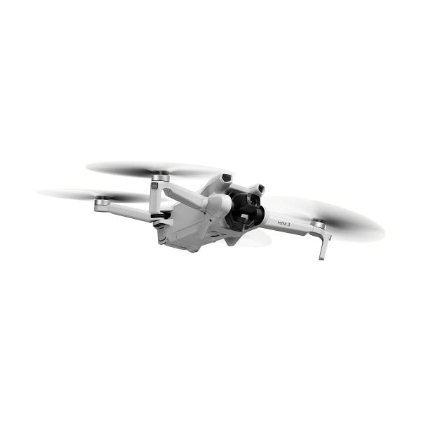 The DJI Mini 3 + Smart Controller drone, with its sleek white design, four extended arms and rotating propellers, flies against a white background. The front camera adds to its compact and modern look.