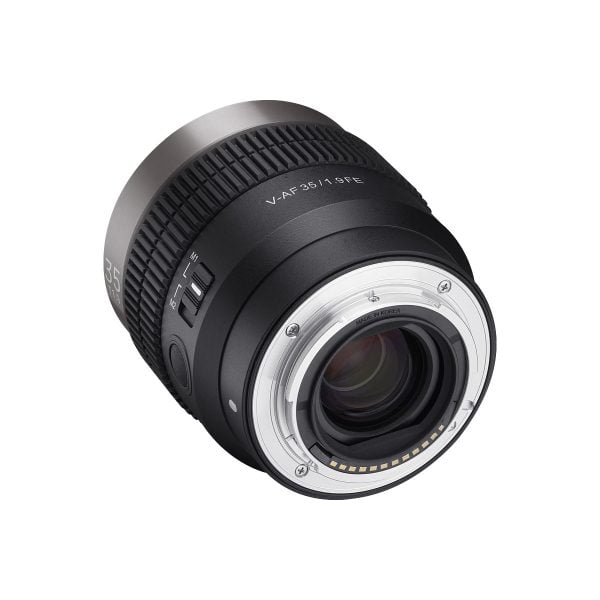 Lähikuva Samyang V-AF 35mm T1.9 -objektiivista Sony FE:hen, jossa näkyy sen metallinen objektiivikiinnitys, lasielementit, elektroniset koskettimet, tarkennusrengas, jossa on merkityt kytkimet, ja yksityiskohtaiset merkinnät takakulmasta.