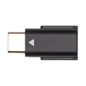 A DJI Mic Dual Kit wireless microphone system USB-C adapter, black, with a small white arrow on the body, featured on a white background.