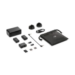 DJI Mic Dual Kit wireless microphone system shown on a white background: two transmitters, one receiver, windscreens, charging case, cables, adapters, microSD cards and black drawstring bag.