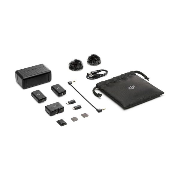 DJI Mic Dual Kit wireless microphone system shown on a white background: two transmitters, one receiver, windscreens, charging case, cables, adapters, microSD cards and black drawstring bag.