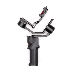 DJI RS 3 Mini -gimbaali on mustalla kädessä pidettävä kameranvakain, jossa on ergonominen kahva, ohjauspainikkeet ja L-muotoinen kiinnike kameran kiinnittämistä varten, kuvassa valkoista taustaa vasten.
