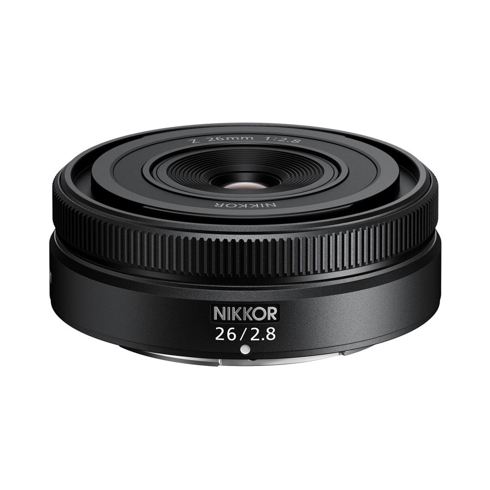 Nikon Nikkor Z 26mm f/2.8 -objektiivi, jossa on kompakti pancake-tyylinen muotoilu, kuvioitu tarkennusrengas ja yksityiskohtaiset merkinnät etu- ja sivupuolella valkoista taustaa vasten.