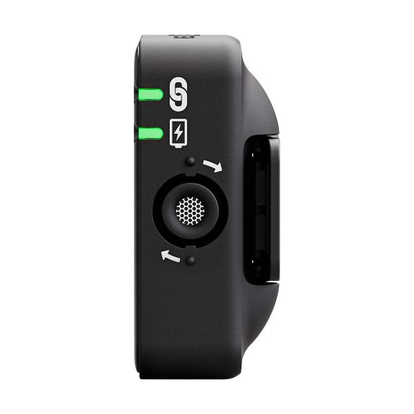 Rode_Wireless_ME_005 Lähikuvassa Rode Wireless ME -langaton mikrofonijärjestelmä näyttää vihreät merkkivalot, salamakuvakkeen, pyöreän aukon, jossa on nuolia, ja liukupainikkeen sen mustalla puolella valkoista taustaa vasten.