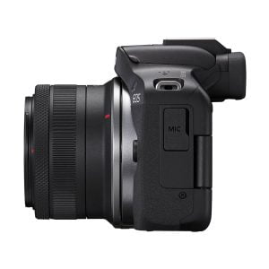 Sivukuva Canon EOS R50 -digitaalikamerasta, jossa on RF-S 18-45mm F4.5-6.3 IS STM -objektiivi, kuvioitu kahva, MIC-merkityt porttisuojat ja osittain näkyvä "EOS" kahvan yläpuolella. Nyt saatavana 100€ alennuksella.