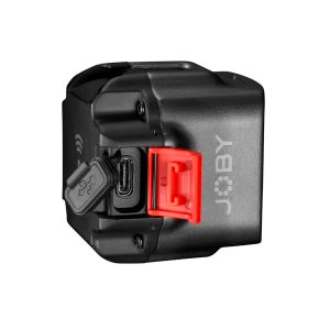 Joby-Beamo-2 Pienikokoinen musta Joby Beamo - LED-valo, jossa on JOBY-logo, punainen salpa ja avoin kumikansi, joka paljastaa sivussa olevan USB-C-portin. Tausta on valkoinen.