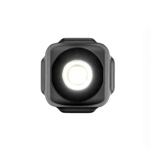 Joby Beamo Mini - LED-valo on pieni, musta, neliönmuotoinen LED-valo, jossa on kirkas pyöreä keskipiste, joka näkyy edestä valkoista taustaa vasten.