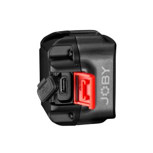 Joby-Beamo-Mini-4 Joby Beamo Mini - LED-valo on musta laite, jossa on näkyvä USB-C-portti, kuminen porttisuojus ja näkyvä punainen salpa sivussa valkoista taustaa vasten.
